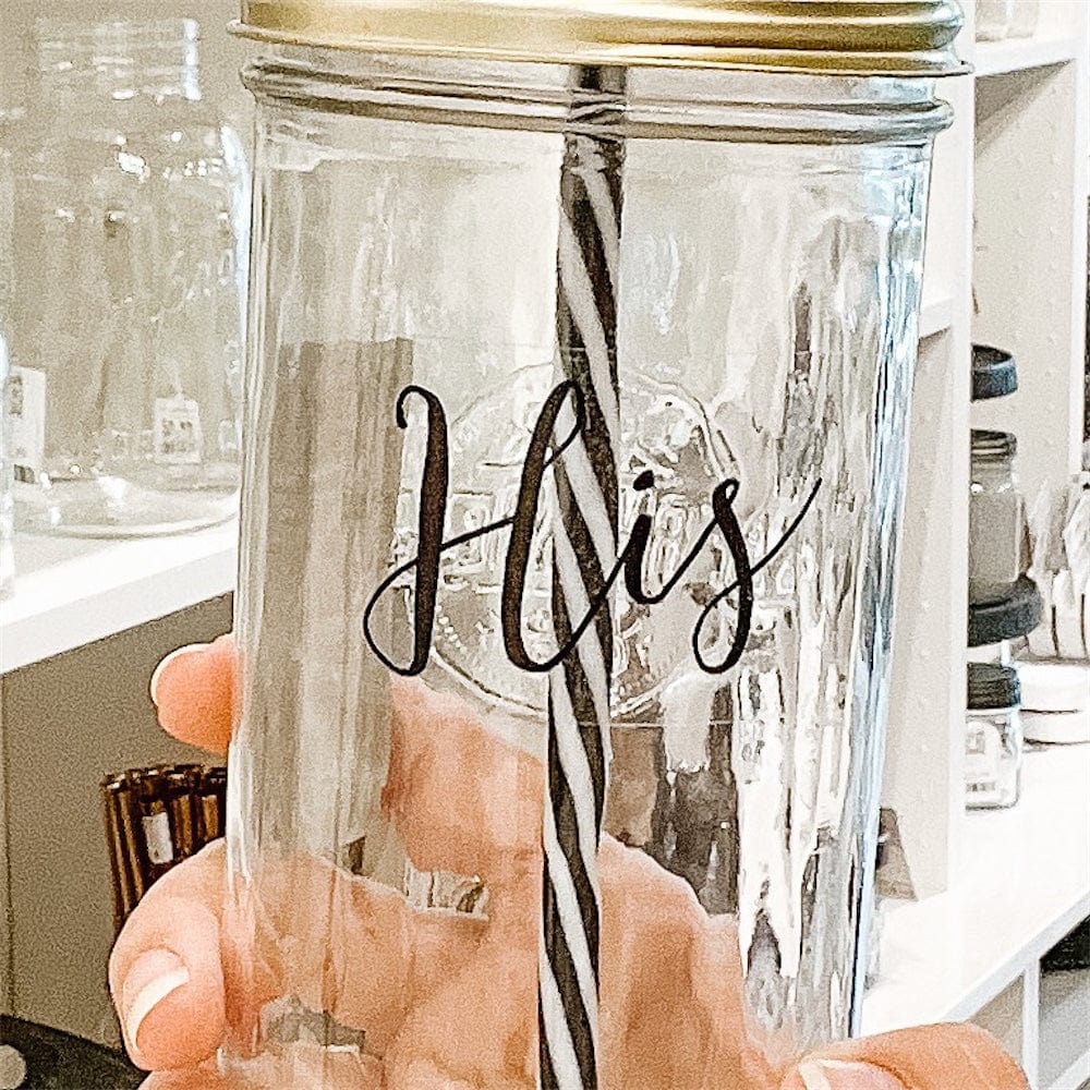 A photo of a mason jar tumbler with a sticker text that says "His"