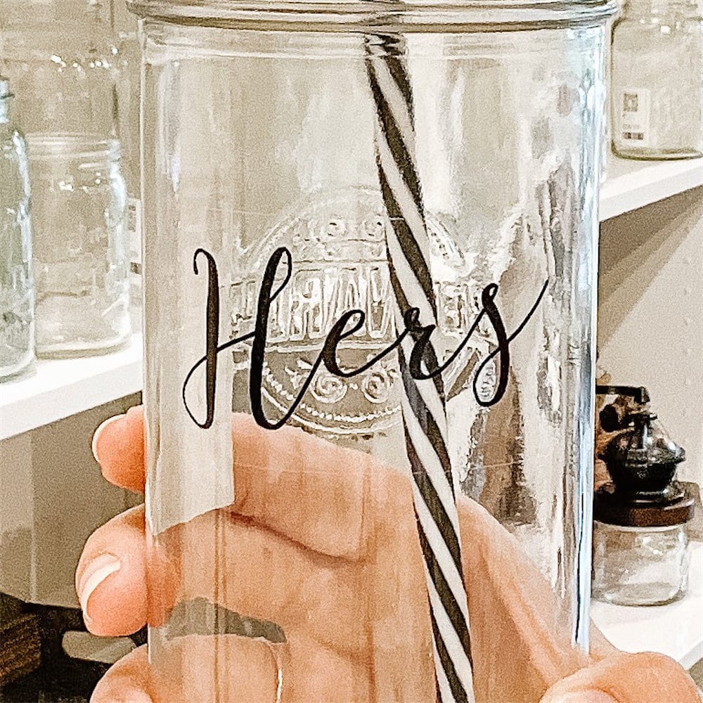A photo of a mason jar tumbler with a sticker text that says "Hers"