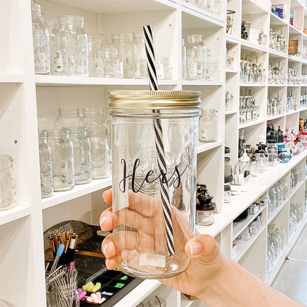 A photo of a mason jar tumbler with a sticker text that says "Hers"