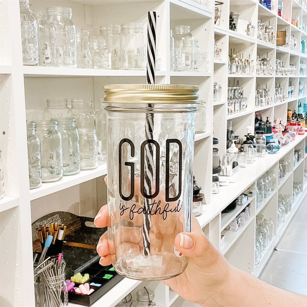 Photo of a mason jar with a print that says God is faithful. It has gold lid and a black and white straw.