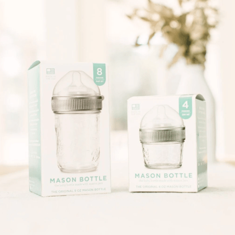 Photo of 8oz and 4oz mason bottle in a box. Photographed on a white countertop with a plant in the backdrop.