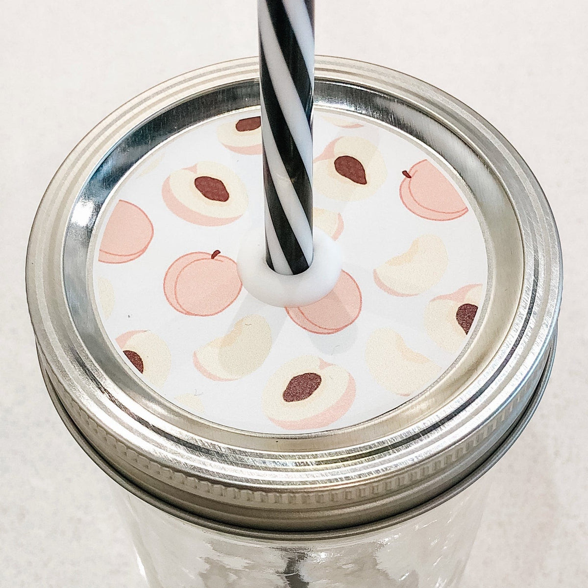Close up photo of a mason jar straw lid with a pictures of a peaches