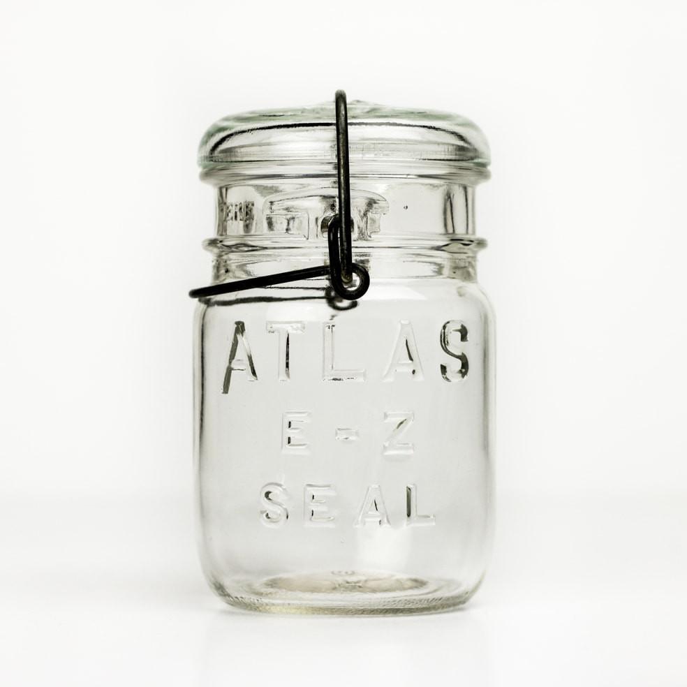 Vintage 3/4 pint Atlas E-Z Seal mason jar with wire bail and glass lid, against a white background