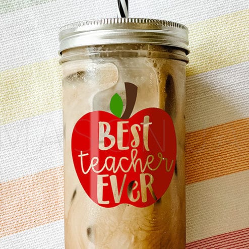 "Best Teacher Ever" print inside a red apple printed on tumbler with iced coffee against a striped picnic fabric.