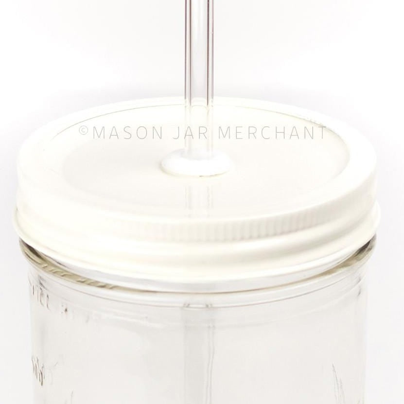 A close up picture of an all white straw lid on a 24 oz reusable glass mason jar with a reusable glass straw