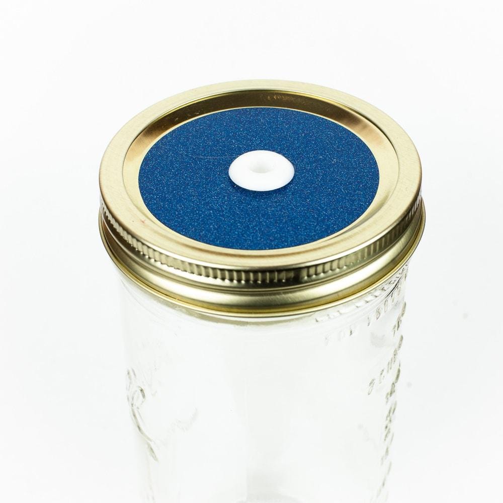 Deep blue green Glitter Mason Jar Straw Lid on a golden lid against a white background.