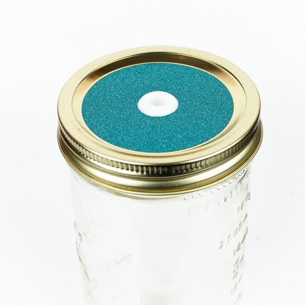 Dark teal Glitter Mason Jar Straw Lid on a golden lid against a white background.