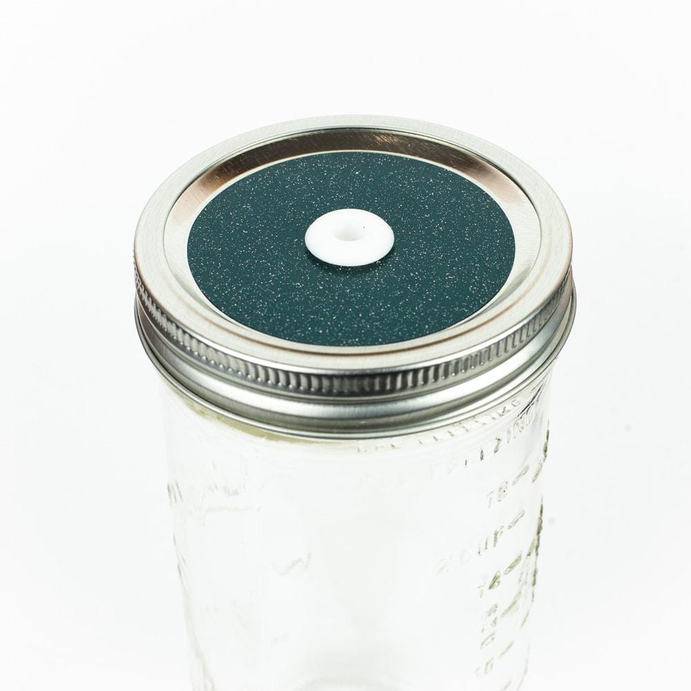 Emerald green Glitter Mason Jar Straw Lid on a silver lid against a white background.