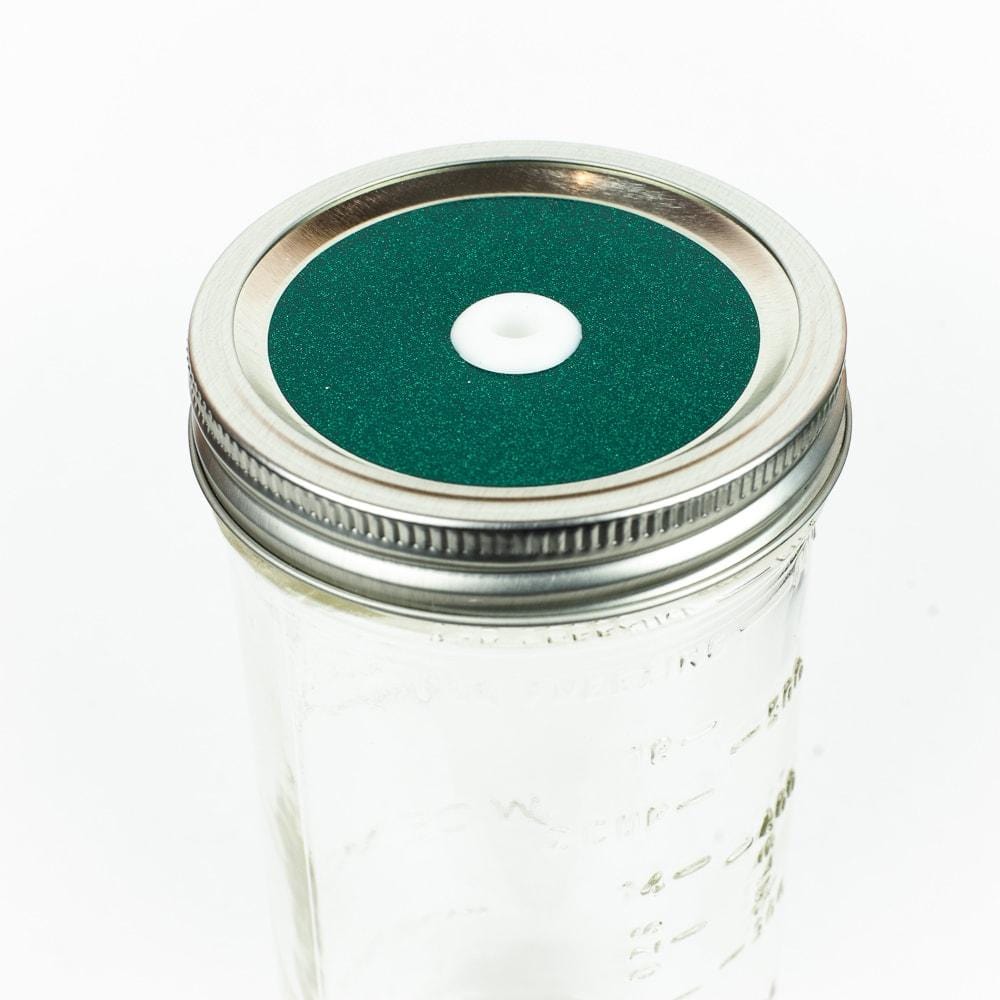Green Glitter Mason Jar Straw Lid on a silver lid against a white background.