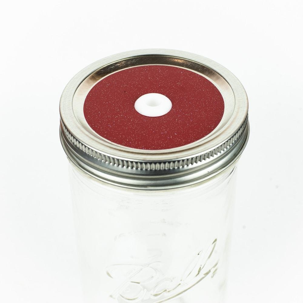 Ruby red Glitter Mason Jar Straw Lid on a silver lid against a white background.