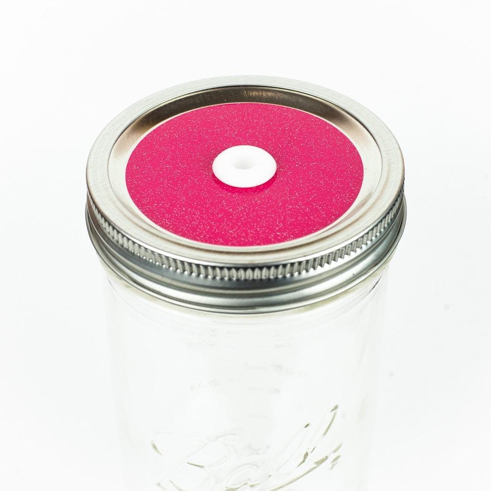 Hot pink Glitter Mason Jar Straw Lid on a silver lid against a white background.