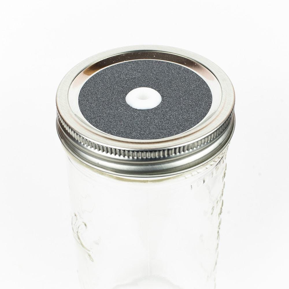 Medium grey Glitter Mason Jar Straw Lid on a silver lid against a white background.