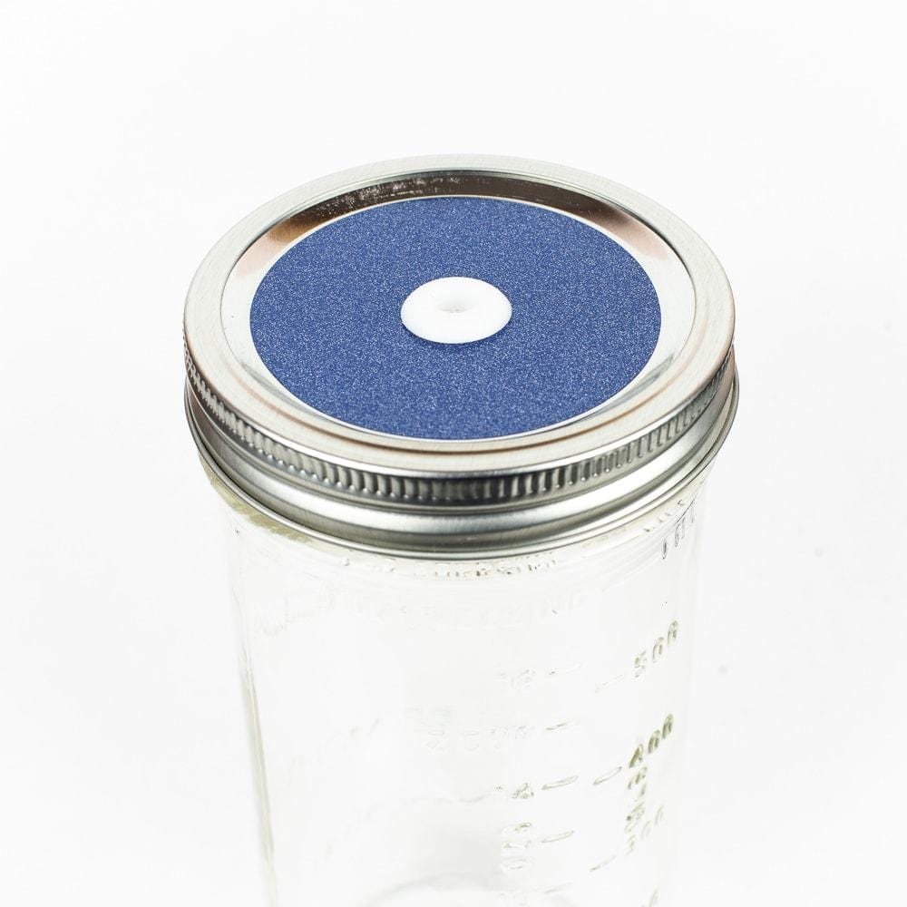Periwinkle Glitter Mason Jar Straw Lid on a silver lid against a white background.