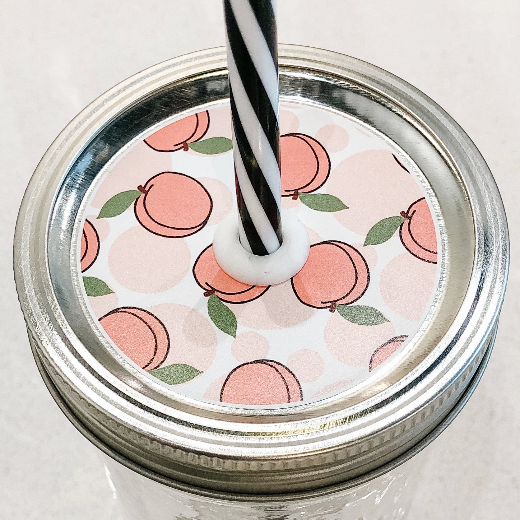 Photo of a peach mason jar straw lid with a black and white straw