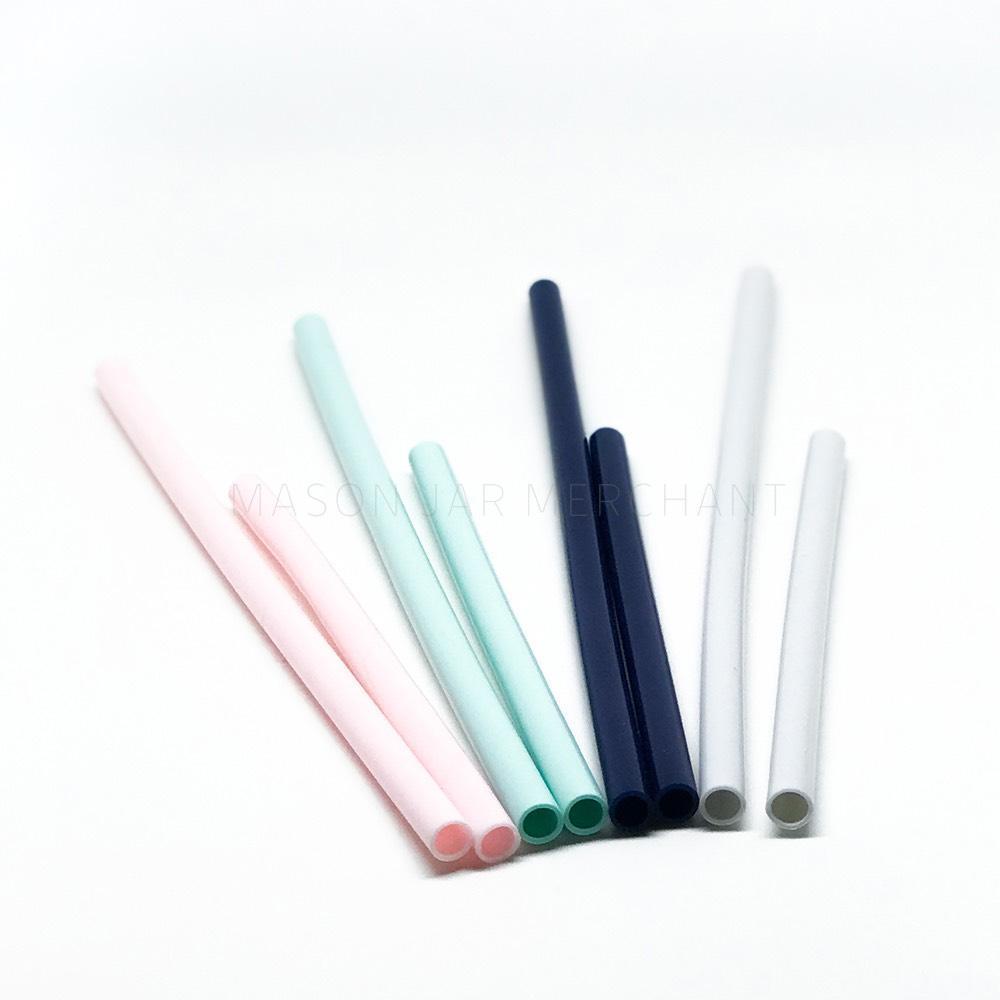 8 reusable silicone straws sit on a white background. Some short and some long, in pink, aqua, navy blue and grey