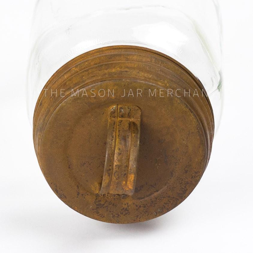 close up of a rusty lid with handle on a glass mason jar on a white background