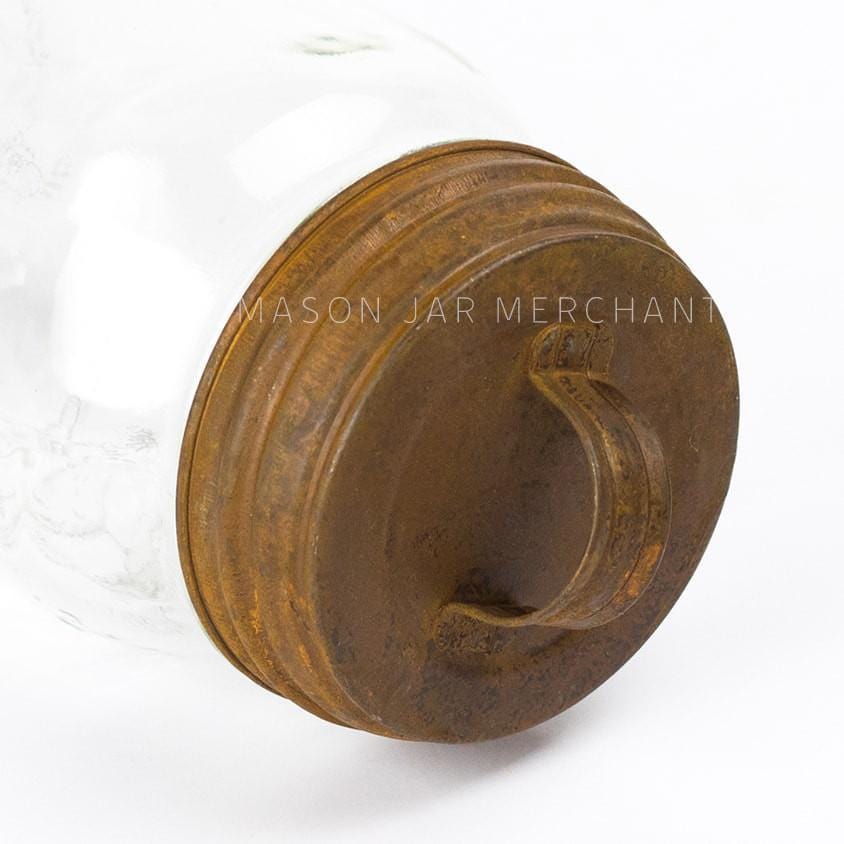 close up of a rusty lid with handle on a glass mason jar on a white background