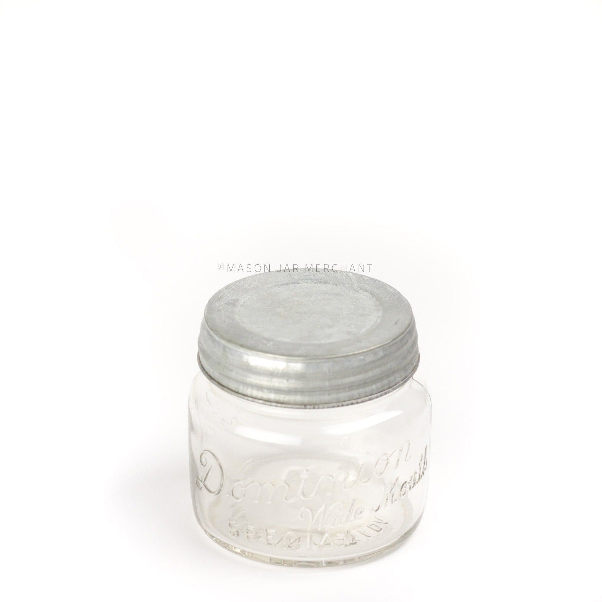 a close up of a rustic galvanized wide mouth lid on a glass mason jar on a white background