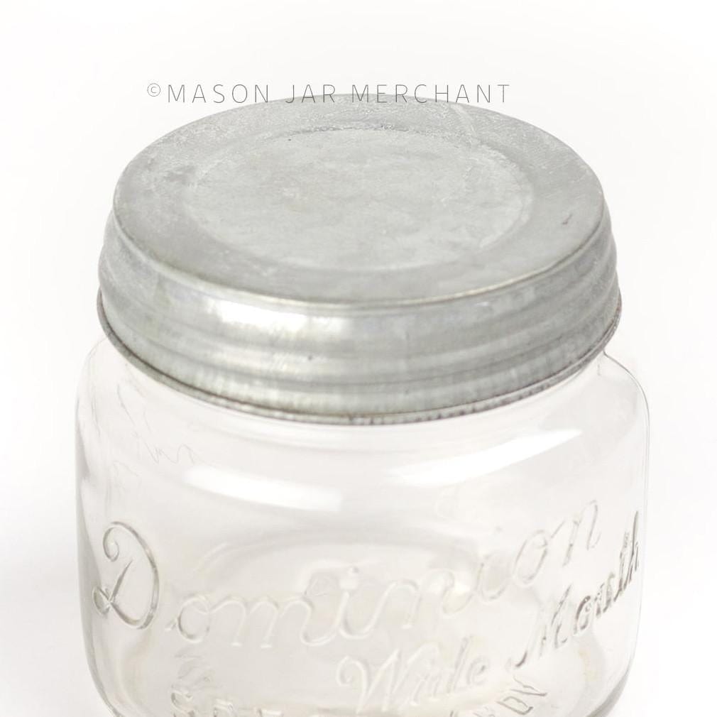a close up of a rustic galvanized wide mouth lid on a glass mason jar on a white background