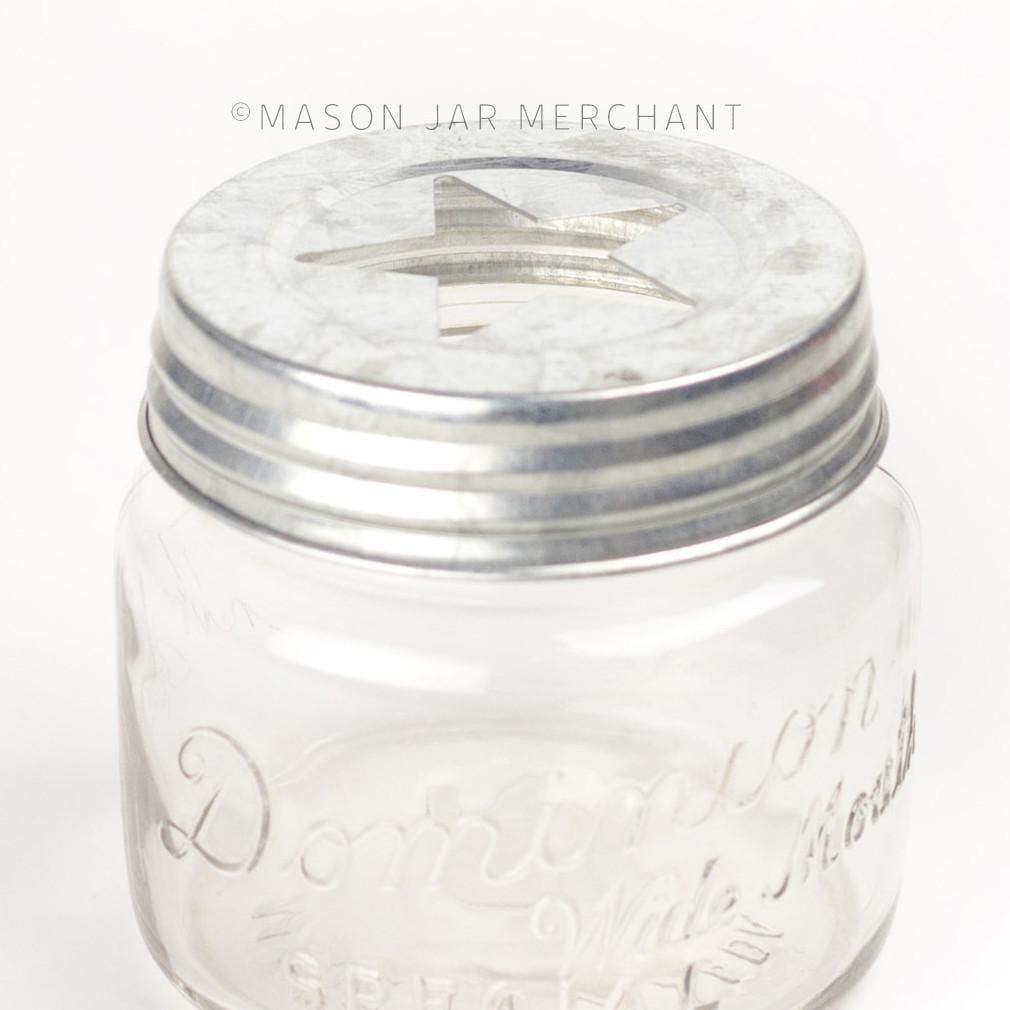 close up of a rustic galvanized star cut out lid on a glass mason jar on a white background