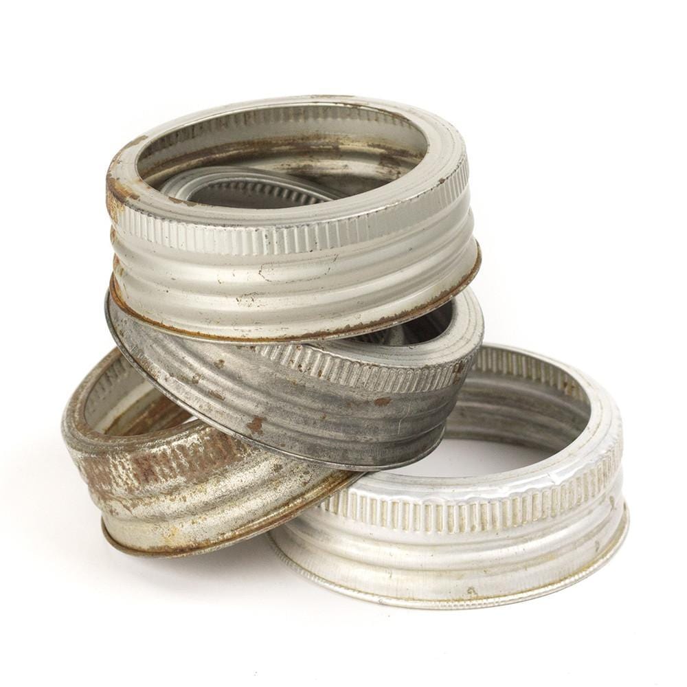 stack of four vintage aluminum GEM mouth mason jar rings on a white background
