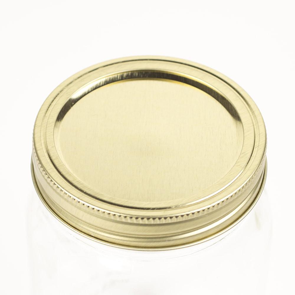 close up of a gold wide mouth canning lid and ring on a white background