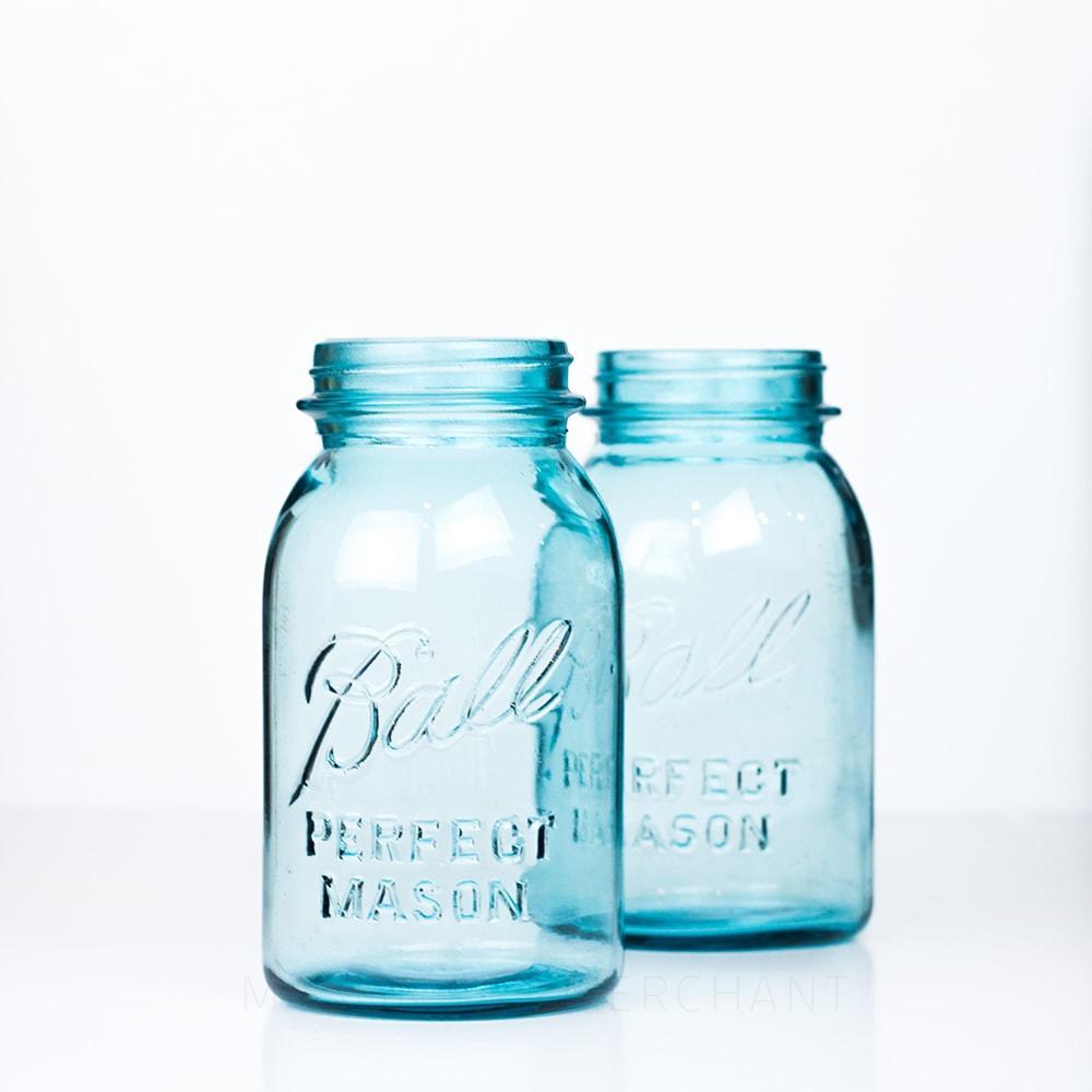 Two Vintage blue Ball regular mouth quart mason jar against a white background