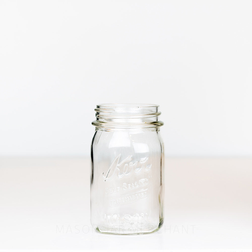 Vintage regular mouth pint mason jar with Kerr  self-sealing logo, against a white background 