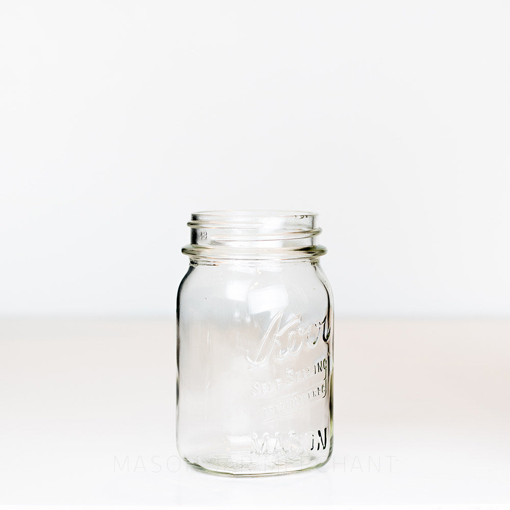 Vintage regular mouth pint mason jar with Kerr self-sealing logo, against a white background 