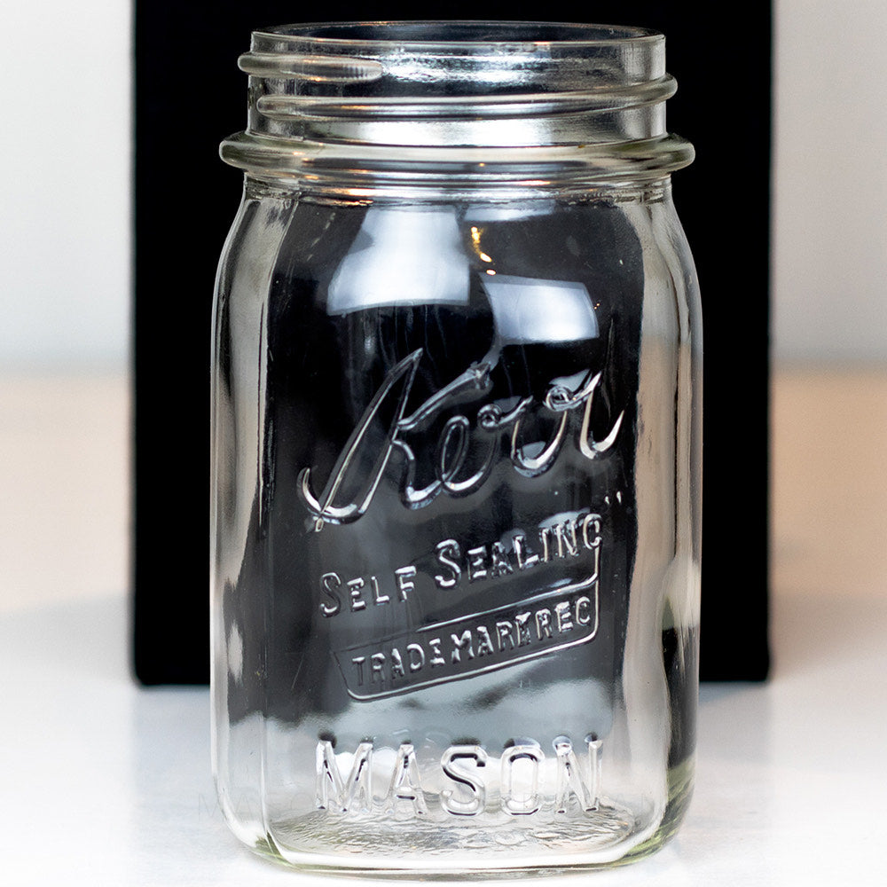 A close up of a Vintage regular mouth pint mason jar with Kerr self-sealing logo, against a white background