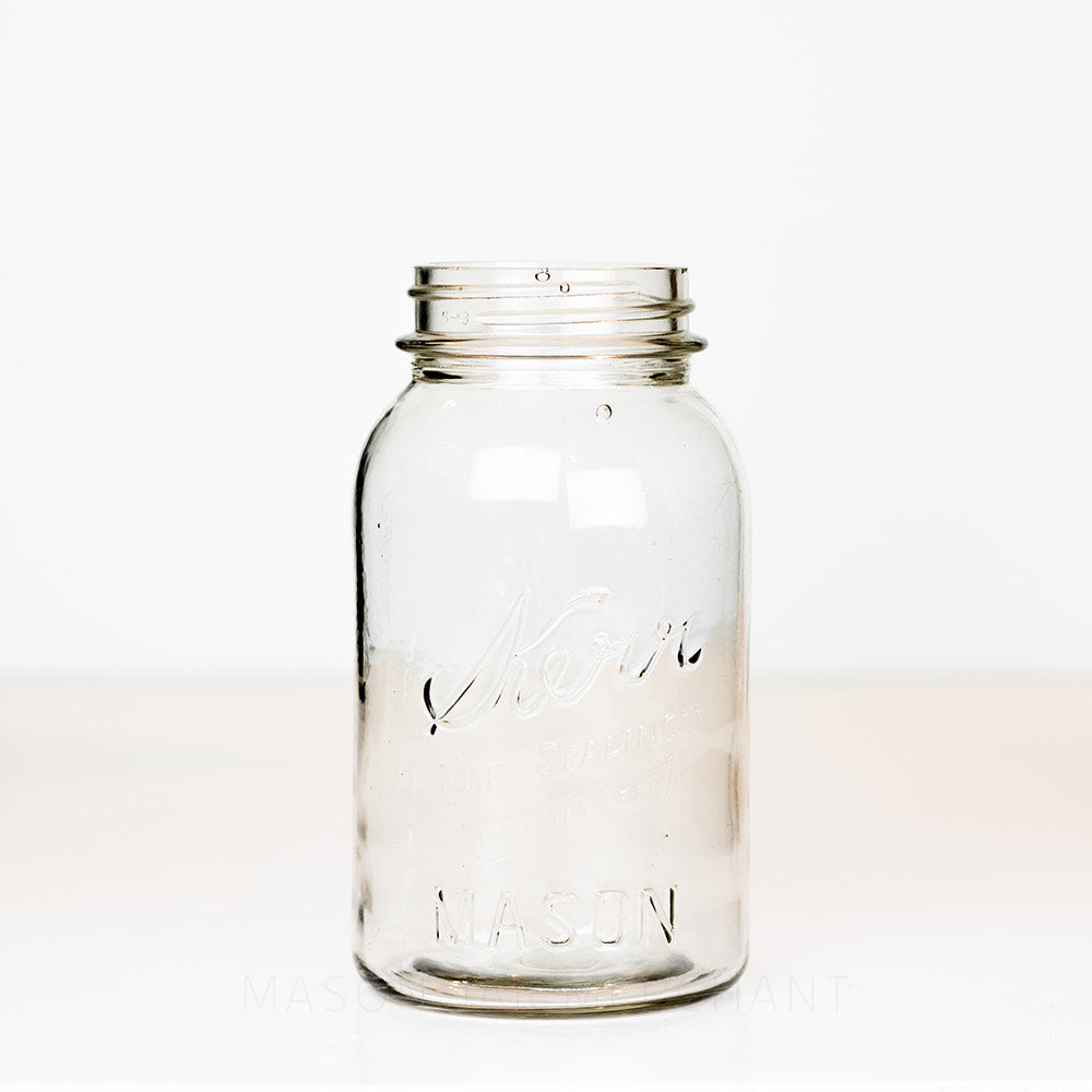 Vintage Kerr regular mouth quart mason jar with logo showing on a white background