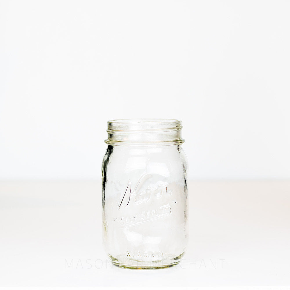 Regular mouth pint mason jar with a Kerr "self-sealing" logo on a white background 
