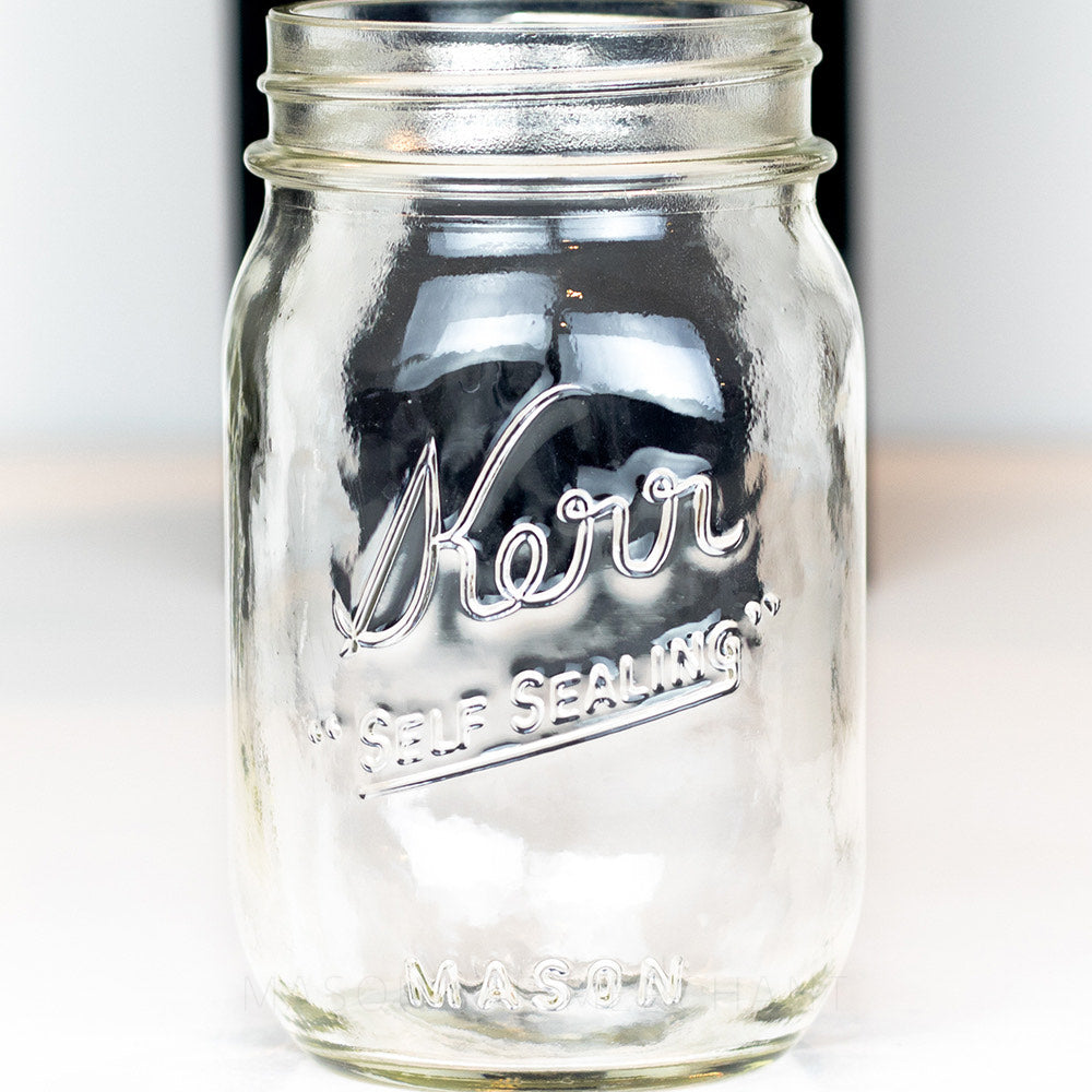 Regular mouth pint mason jar with a Kerr "self-sealing" logo on a white background 