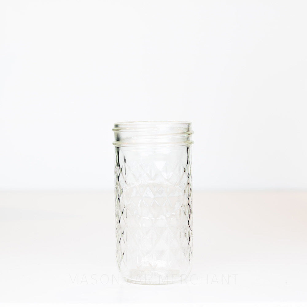 Unique 10 oz regular mouth mason jar. Tall and thin with a quilted pattern all over except for space to add a label. On a white background