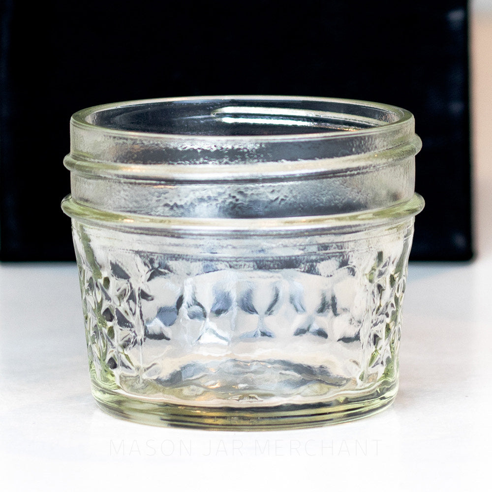 A close up of a 3 oz. regular mouth mason jar with a quilted pattern on a white background