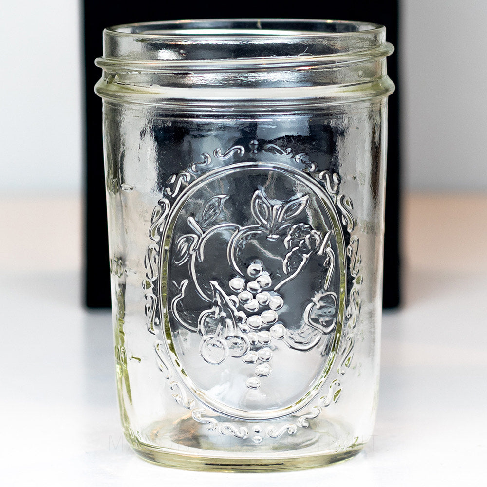 Close up of a Wide mouth pint Ball mason jar with decorative fruit design against a white background