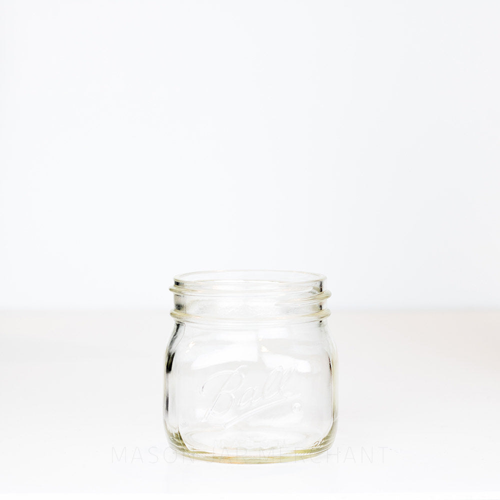 Ball wide mouth pint mason jar with a short square body against a white background 