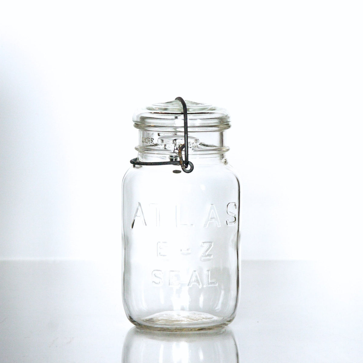 Vintage Atlas E-Z Seal quart mason jar with  wire bail and glass lid, against a white background 
