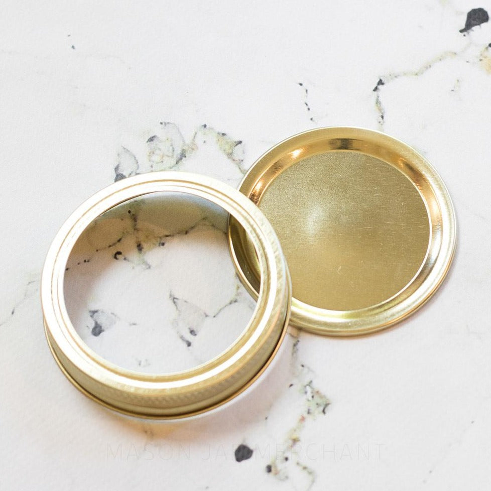 Plain Gold Regular Mouth (Standard) Mason Jar Lid and Ring, shown on a marble background.