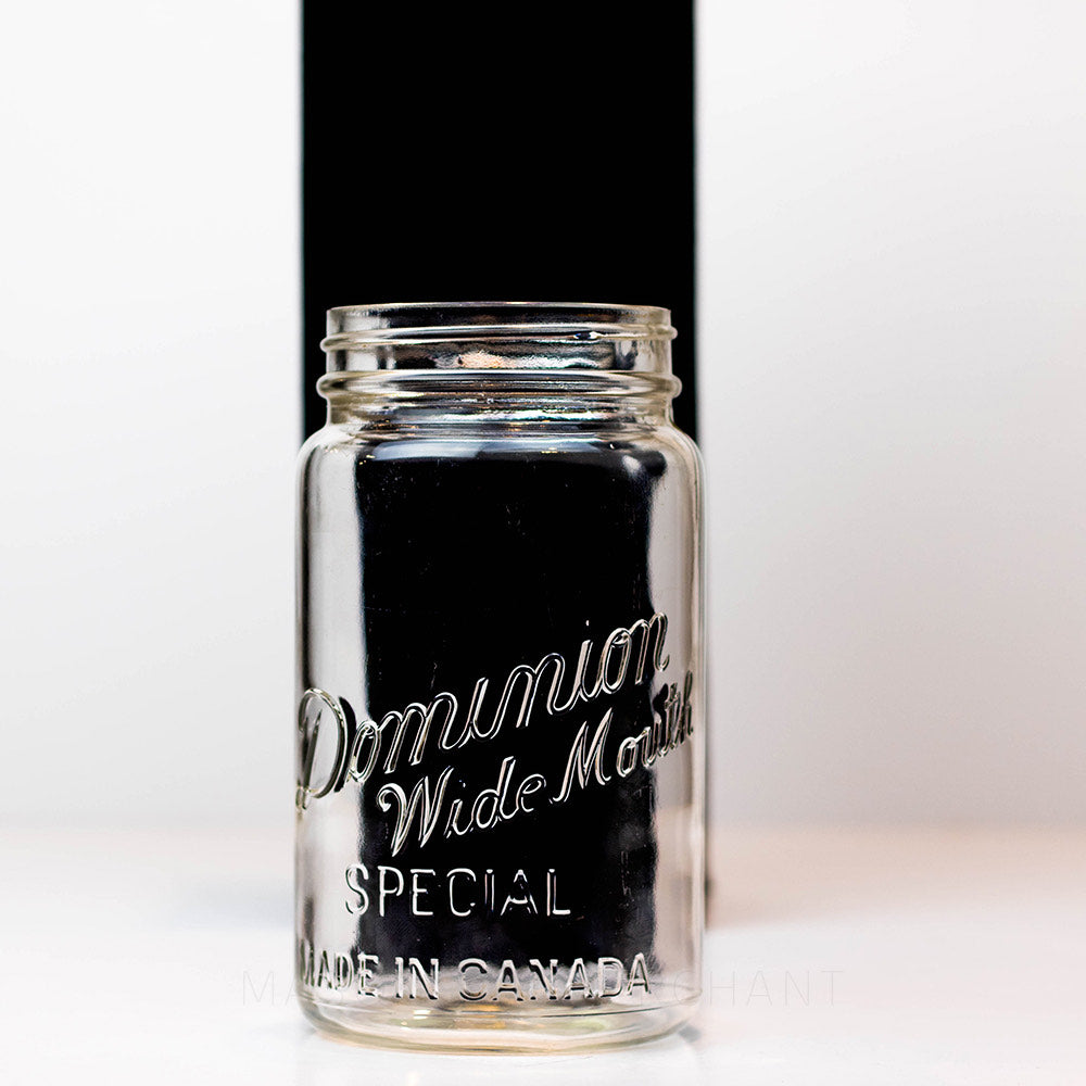 A close up of a Vintage wide mouth Dominion mason jar quart against a white background