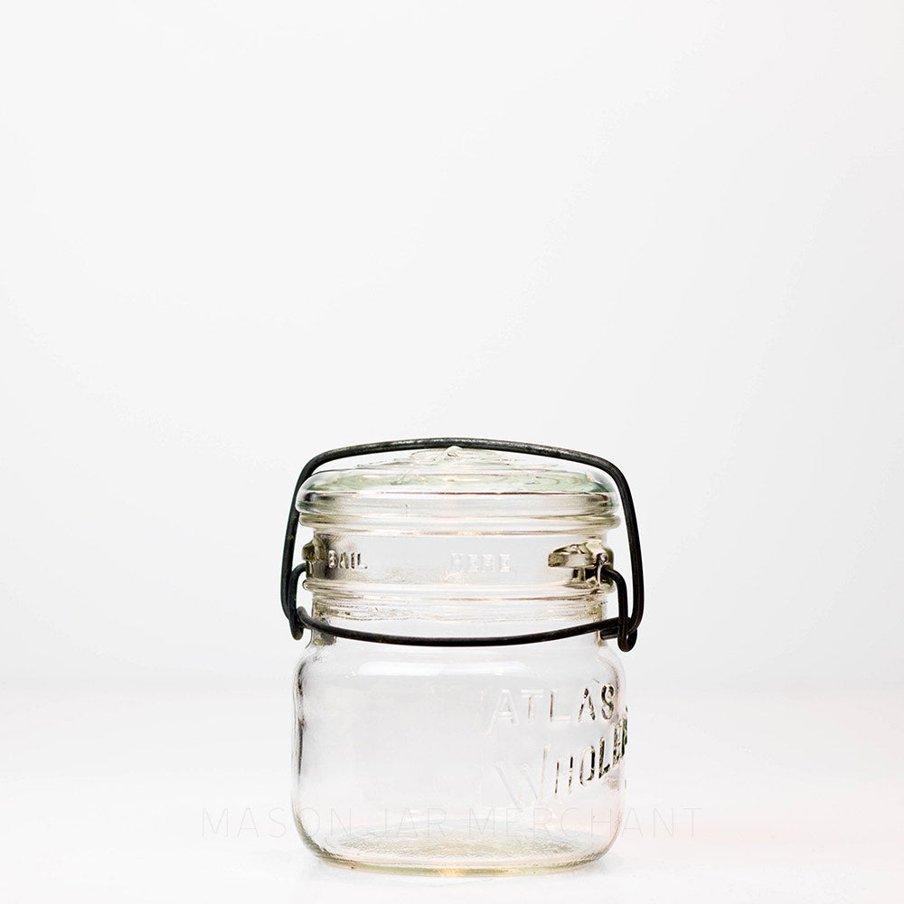 A front view of Vintage 1940s Atlas Wholefruit wide mouth wire bail mason jar against a white background