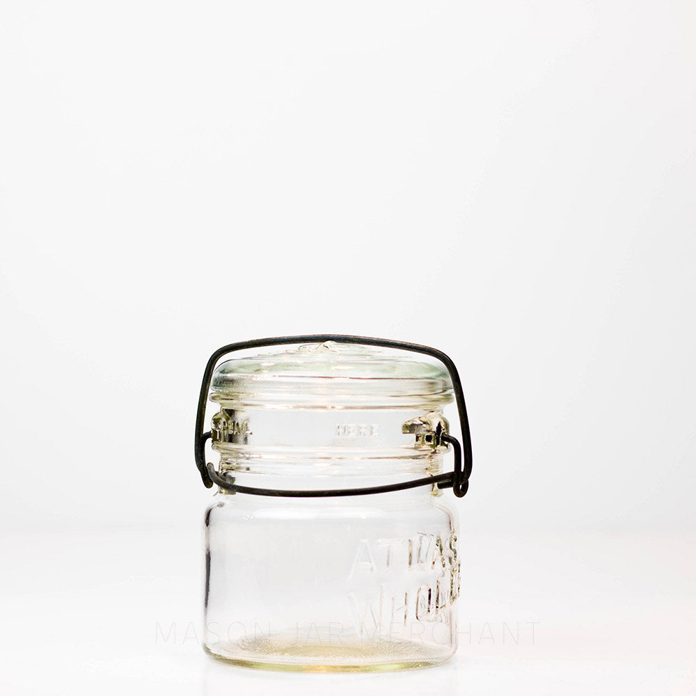 A front view of a Vintage Atlas Wholefruit wide mouth wire bail mason jar against a white background