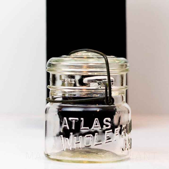 A close up of a Vintage Atlas Wholefruit wide mouth wire bail mason jar against a white background