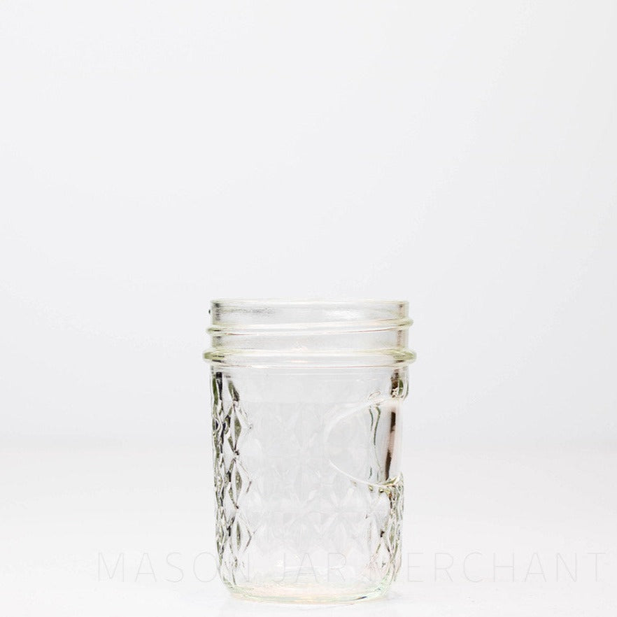 Regular mouth half pint mason jar with a quilted pattern and space to add a label, against a white background