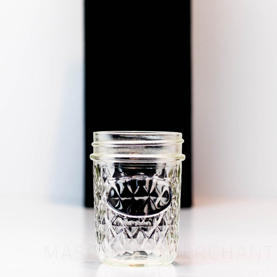 A close up details of a Regular mouth half pint mason jar with a quilted pattern and space to add a label, against a white background