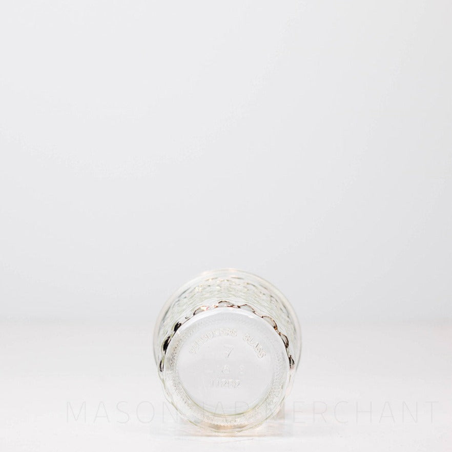 Bottom of a Regular mouth half pint mason jar with a quilted pattern against a white background