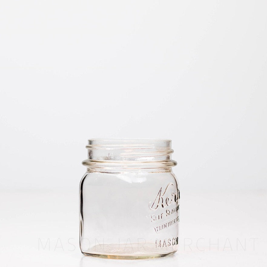 Side view of Regular mouth half-pint mason jar with Kerr self-sealing logo, against a white background