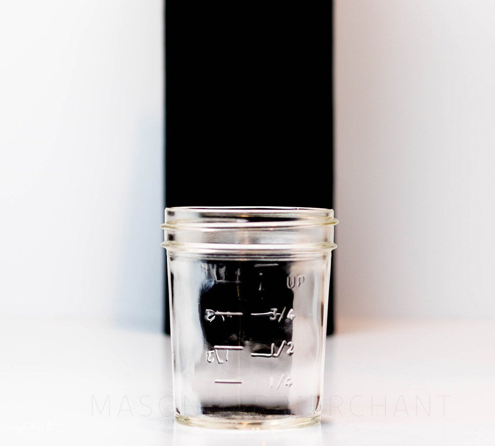 Back of a Regular mouth half pint mason jar with straight sides against a white background. It has a measurements engraved.
