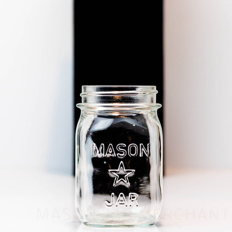 close up of a Regular mouth pint mason jar with mason star logo on a white background