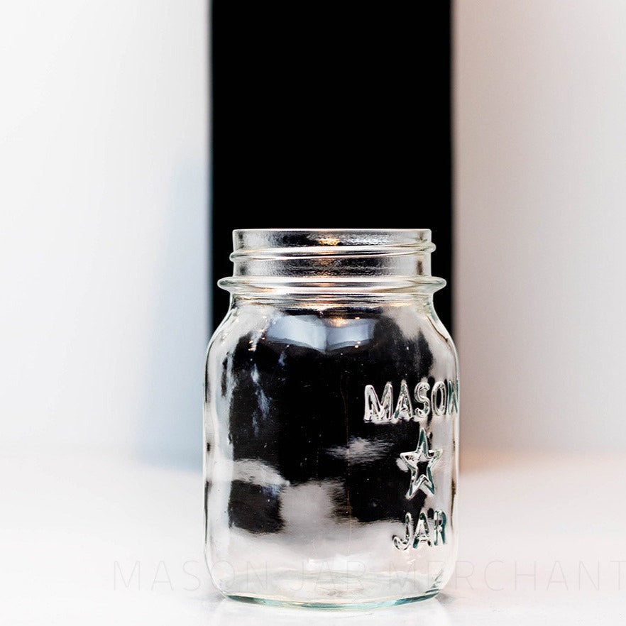 side view of a Regular mouth pint mason jar with mason star logo on a white background